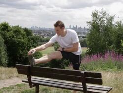 Male stretching on bench in park Stock Footage