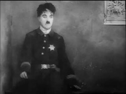 B/W 1917 dazed policeman Charlie Chaplin twitches on bench + stands up pulling needle from buttocks Stock Footage