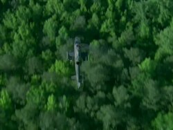 Air-to-air shot looking down on U.S. Army Cobra attack helicopter running at high speed over small town setting Stock Footage
