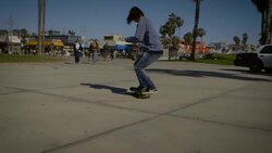 dolly of skater filming himself doing an ollie venice California skatepark Stock Footage