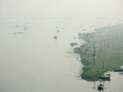 Devotees step off to bathe from green promontory on the banks of the river Ganges, boats out on the river. Kumbh Mela, India Stock Footage