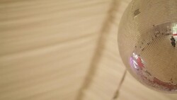 Low angle footage of illuminated disco ball. Glowing sphere is rotating while hanging from ceiling in nightclub. Stock Footage