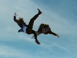 Wide shot two business men in midair after jumping on trampoline / one kicking other in midair / both men bounce up again Stock Footage