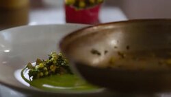 In restaurant kitchen, chef serves succotash from skillet onto dinner plate Stock Footage
