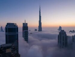 Time Lapse of Burj Khalifa rising above fog at dawn, night to day Stock Footage