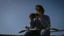 skater sitting on dog bowl looking at his phone and filming in venice skatepark california Stock Footage