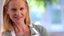 Housewife in apron stands in kitchen with arms crossed, smiles at camera Stock Footage