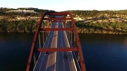 Pennybacker Bridge or 360 Bridge or Capital of Texas Highway Bridge at Sunset on the Colorado River or Town Lake Spring Time Aerial Flying Directly Over the Top of the Bridge Stock Footage