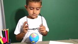 Boy looking through magnifying glass at globe Stock Footage
