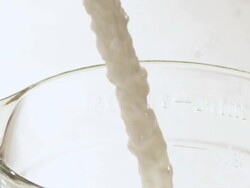 CU SLO MO Milk pour landing in big measuring cup creating splash / Los Angeles, California, United States Stock Footage