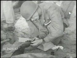1944: BATTLE OF KWAJALEIN: WS PAN (R) Destroyed beach after battle, rubble. VS Grave Registration officer taking thumb print of burnt hand of deceased U.S. Marine (Killed in Action, KIA). VS Marines burying soldier. WWII, Pacific Front, aftermath Instructional Video