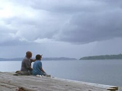 WS Grandfather and grandson sitting on pier near lake / Washington State, USA Stock Footage