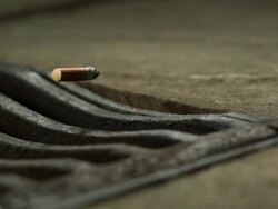 High Speed Cigarette falling in to drain, medium shot Stock Footage