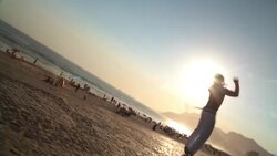 Capoeira martial artist cartwheels and flips backwards across Brazilian beach boardwalk Stock Footage