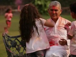 Two kids playing holi festival with his grandfather in a lawn  Stock Footage