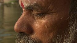 An old man meditates near a bather in a sea in India. Stock Footage