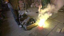 A metal caster fills molds with molten metal from a furnace at a foundry. Stock Footage