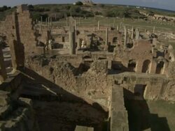 High Angle pan-left tilt-up - Columns cast shadows across the ruins of Leptis Magna. / Khoms, Libya Stock Footage
