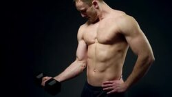 beautiful athlete trains with a dumbbell on a black background Stock Footage