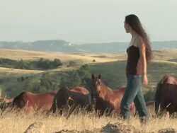 MS TS American Indian young woman walking on great plains in grass near horse herd / Pine Ridge, South Dakota, United States    Stock Footage
