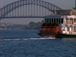 CU revolving paddles of paddle boat zooms out WA Harbour Bridge, Sydney , Australia Stock Footage