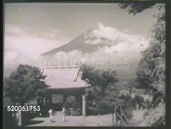 1942: JAPAN: WS Unidentifiable Japanese male rowing boat on Lake Kawaguchi lower frame, Mount Fuji BG. HA WS Two unidentifiable males talking in front of temple shrine, cloudy Mount Fuji BG. VS Pagoda tower, Buddha statue. WS Bridge w/ automobiles. Instructional Video