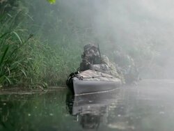 MS Shot of Force Recon soldiers in camouflaged folding boat during reconnaissance mission in jungle with light machine gun in his arms and one soldier pushing boat / Swamp, Virginia, United States Stock Footage