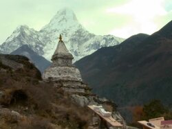 People carrying boxes past a mountainside shrine in the Himalayas of Nepal. Stock Footage