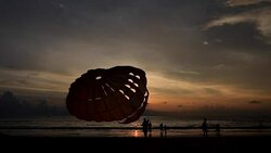 Silhouette of man is preparing para sailing at the sunset beach Stock Footage
