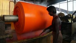 A craftsman stirs a vat of dye in a garment factory. Stock Footage