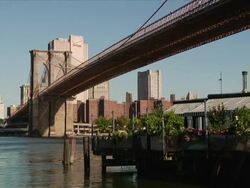 Travel destination. Exterior day shot-Brooklyn Bridge over the East River with a restaurant in the foreground Stock Footage