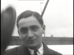 Irving Berlin tips his hat, talks, and smiles during an interview outdoors. News Clip