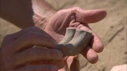 A pair of hands picks up shards of pottery from the sand. Stock Footage