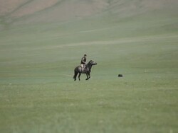 Boy riding horse through nomad camp Stock Footage