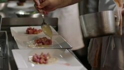 Gourmet chef ladles sauce over steaming scallop dish in restaurant kitchen Stock Footage