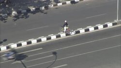 A bicyclist crosses the median of a busy highway in Bandung, Indonesia. Stock Footage