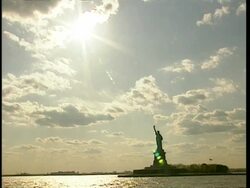 WA tracking shot of Statue of Liberty silhouetted against sunny sky, New York Stock Footage