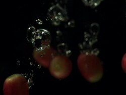 Red grape singles falling into water, black background Stock Footage