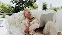 Happy senior woman shopping online on patio sofa Stock Footage