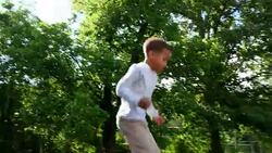 MS LA Father and young son jumping on trampoline in backyard on summer morning Stock Footage
