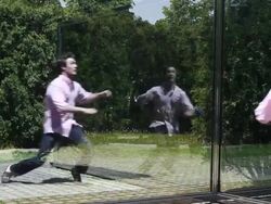 MS Well dressed young man stainding and running next to his own reflection inside  sculpture at park on sunny day / Minneapolis, Minnesota, United States Stock Footage