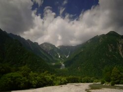 T/L clouds passing over green valley with river in foreground, Kamikochi, Japan Stock Footage