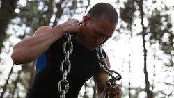 Attractive male doing weight lifting with a chain outdoors in a nature Stock Footage
