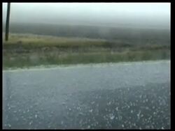 MS large Hail stones pounding road and grass verge, grey overcast sky, USA Stock Footage