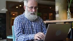 Adult senior bearded man sitting with a laptop Stock Footage