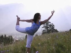 Woman practises yoga moves in mountain meadow Stock Footage