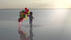 Middle Eastern little girls walking on the water with color balloons - SLOW MOTION Stock Footage