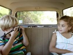 Boy taking a photograph of sister in car Stock Footage