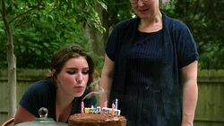 MS TU PAN Smiling teenage girl blowing out candles on birthday cake at family party in backyard of home Stock Footage