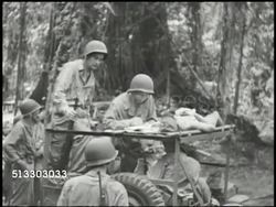 1943: BOUGAINVILLE CAMPAIGN: VS Japanese prisoners of war (POW) eating, on stretcher speaking w/ interpreter, giving intelligence on map to U.S. Marines (intel). WWII, Pacific Front, Battle of Piva Forks, Numa  Numa Trail Instructional Video